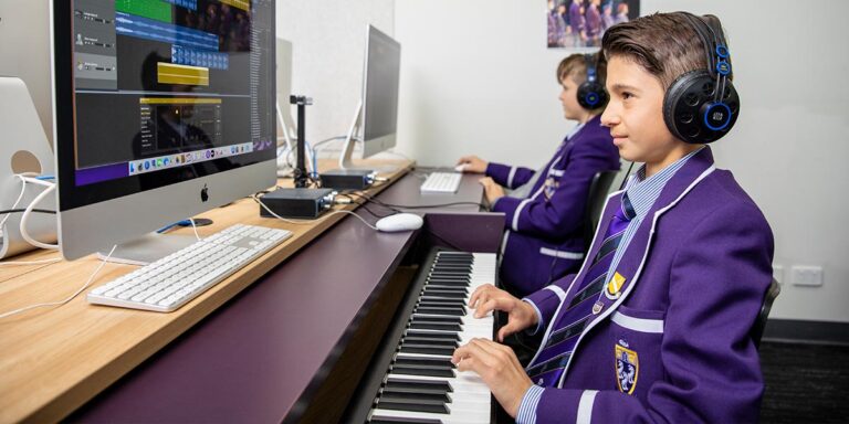 Two students creating music using Apple iMacs and Garage Band and keyboards.
